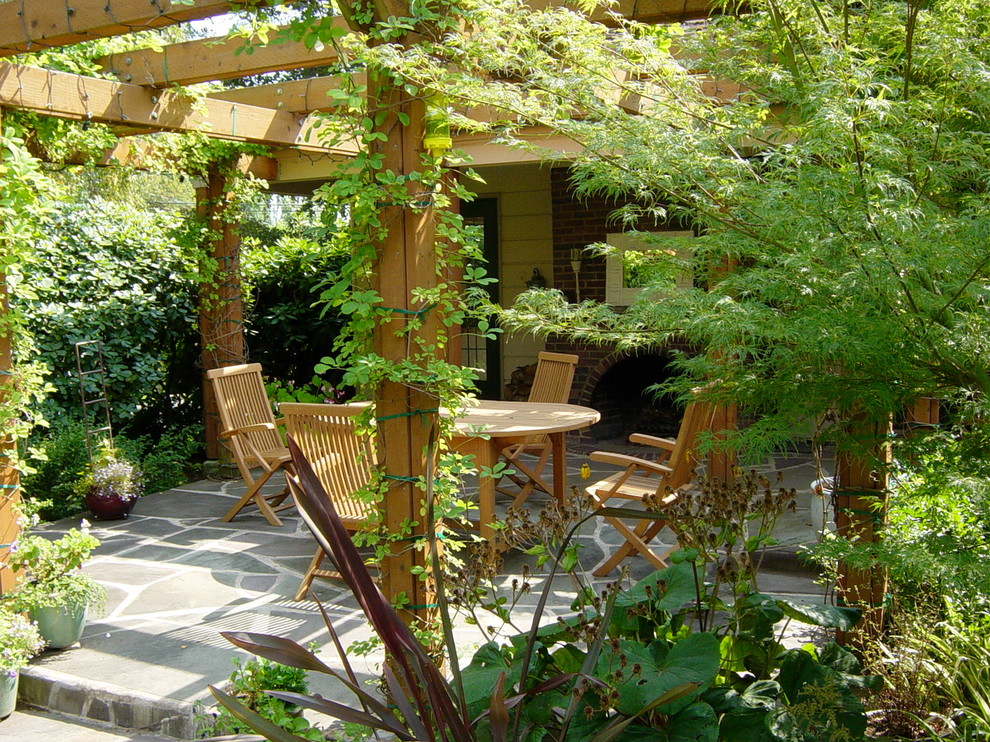 Esempio di un patio o portico chic con un focolare e una pergola