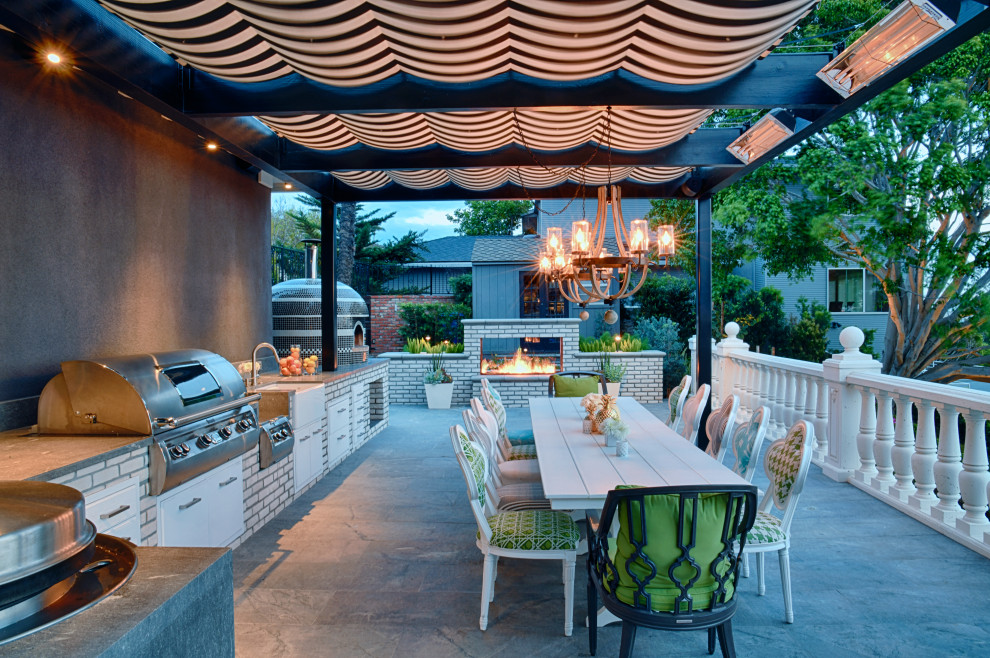 Exemple d'une terrasse arrière moderne avec une cuisine d'été, des pavés en pierre naturelle et une pergola.