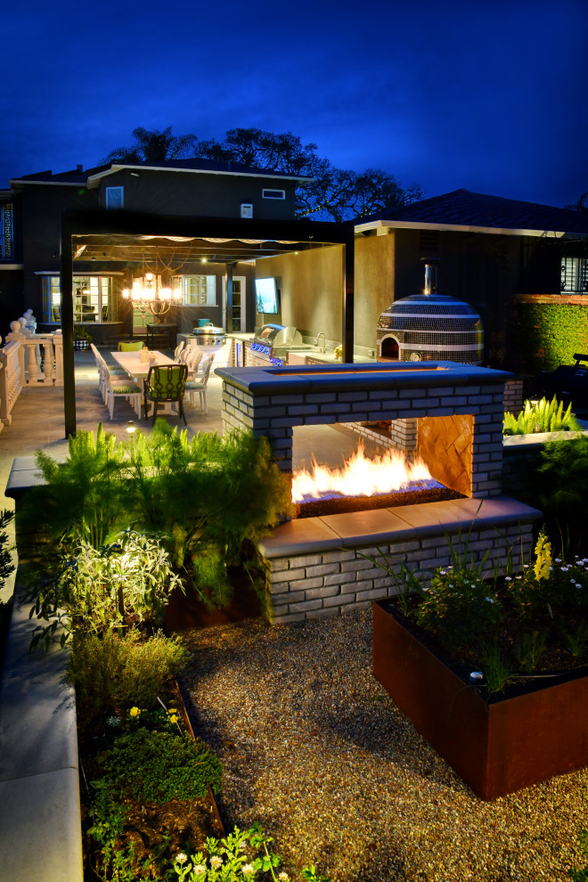 Inspiration for a modern backyard stone patio kitchen remodel in San Diego with a pergola