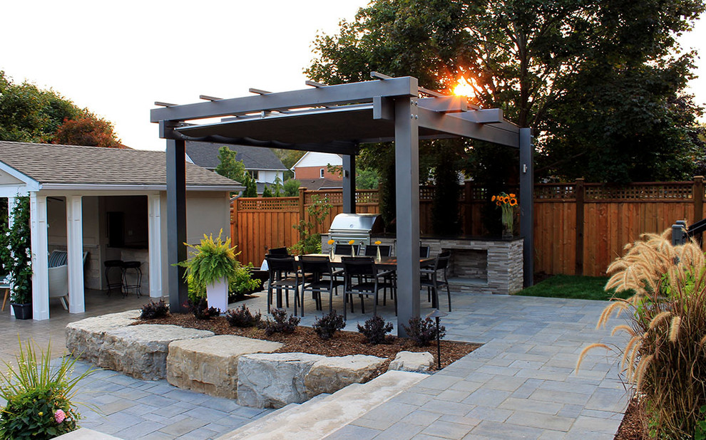 Large contemporary back patio in Toronto with an outdoor kitchen, concrete paving and a pergola.