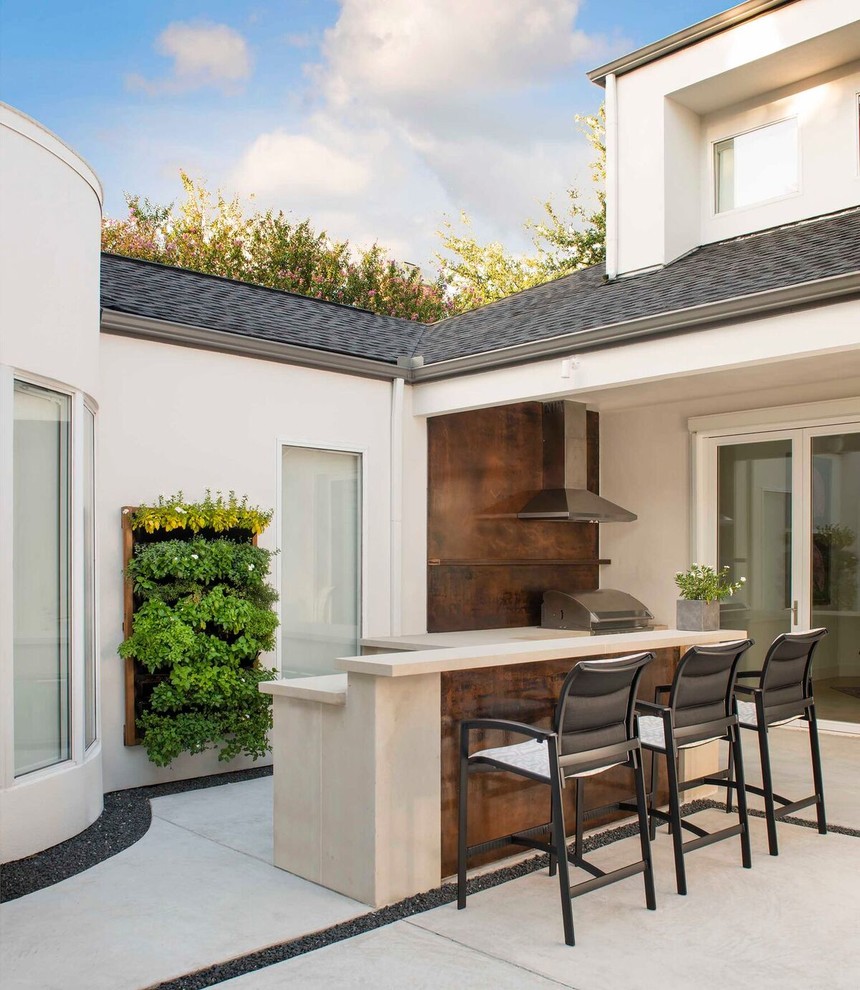 Idée de décoration pour une grande terrasse arrière minimaliste avec des pavés en béton et un foyer extérieur.