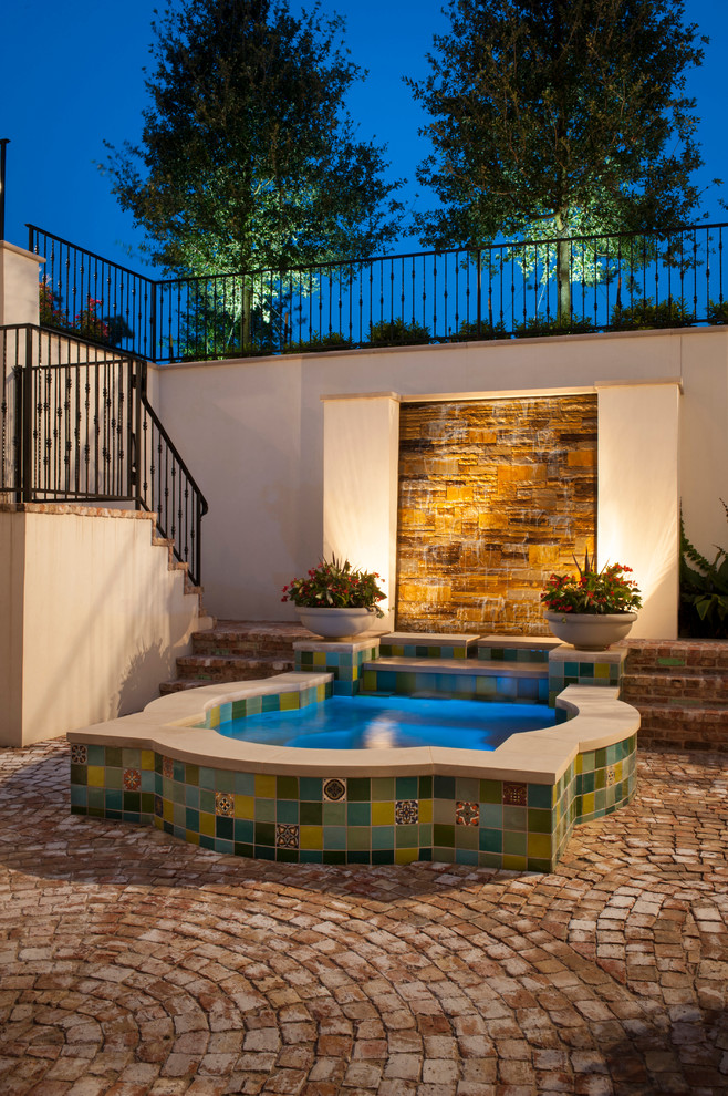 Ejemplo de patio mediterráneo de tamaño medio en patio con fuente y adoquines de ladrillo