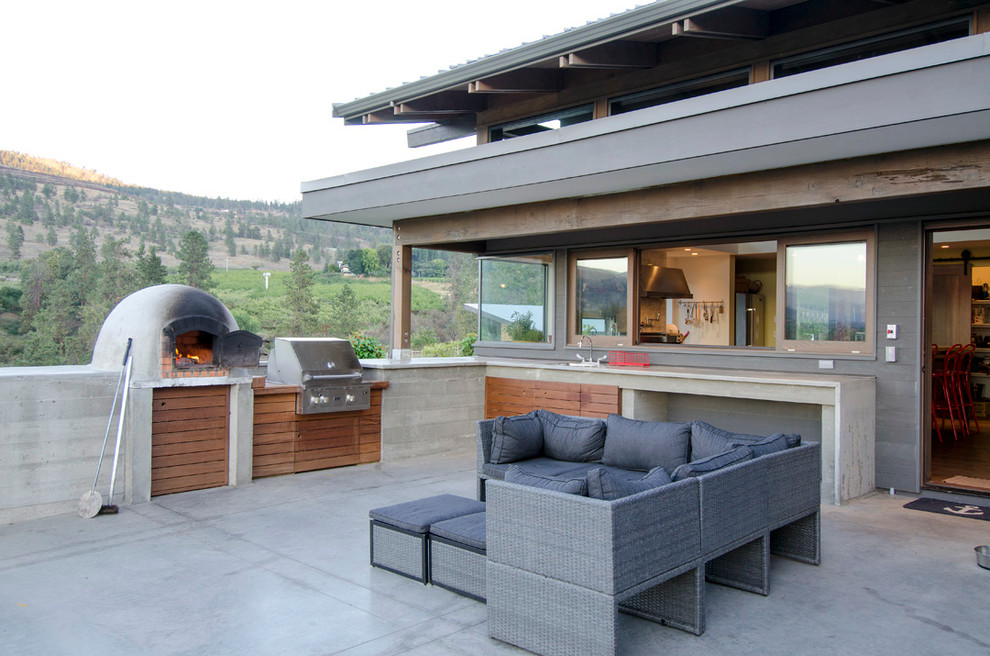 Cette photo montre une grande terrasse arrière moderne avec une cuisine d'été, des pavés en béton et aucune couverture.