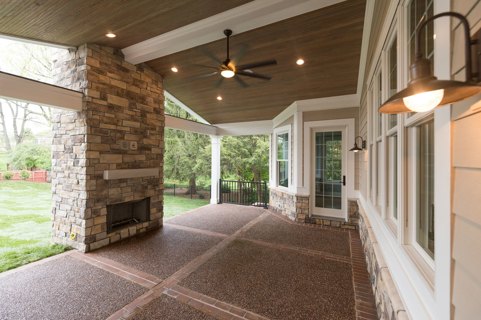 Immagine di un grande patio o portico american style dietro casa con un focolare, un tetto a sbalzo e lastre di cemento