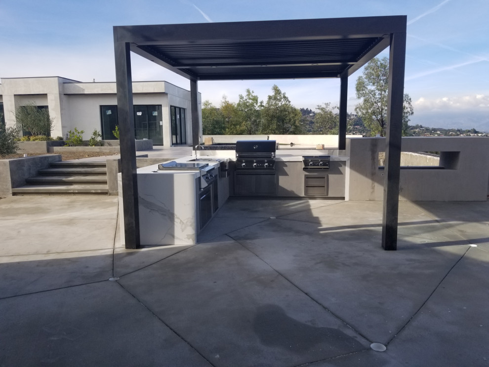 Patio kitchen - large modern backyard patio kitchen idea in Los Angeles with a pergola