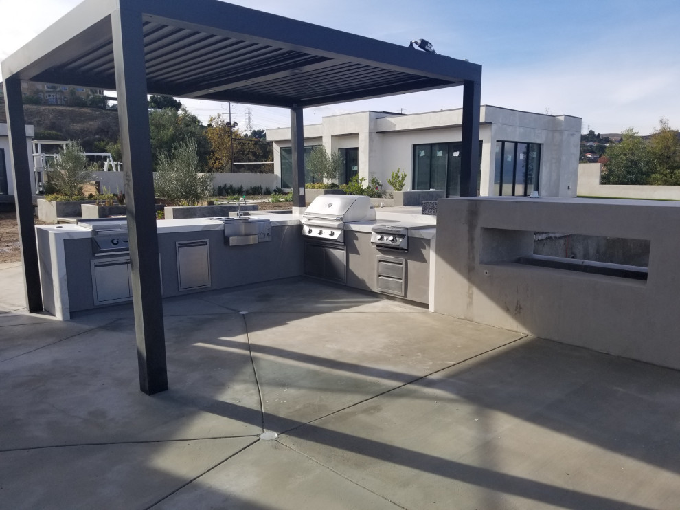 Example of a large minimalist backyard patio kitchen design in Los Angeles with a pergola