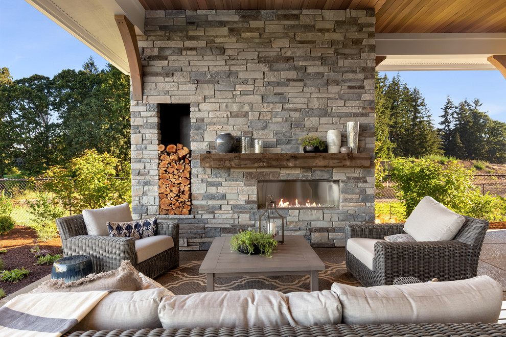 Photo of an expansive rural back patio in Portland with a fireplace, concrete slabs and a roof extension.