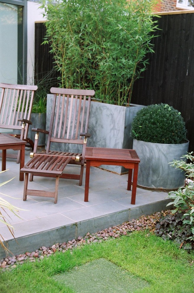 Modelo de patio minimalista de tamaño medio sin cubierta en patio trasero con jardín de macetas y adoquines de piedra natural