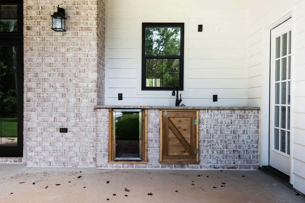 Cette image montre une grande terrasse arrière rustique avec une cuisine d'été, une dalle de béton et une extension de toiture.