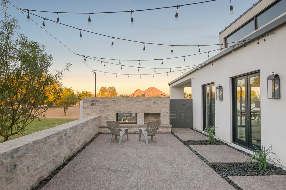 Esempio di un patio o portico minimal di medie dimensioni e davanti casa con un focolare, lastre di cemento e nessuna copertura