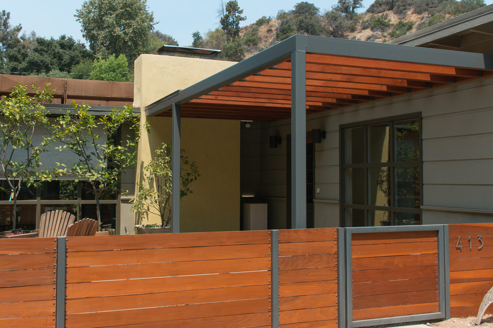 Cette image montre une terrasse avant minimaliste de taille moyenne avec une pergola.