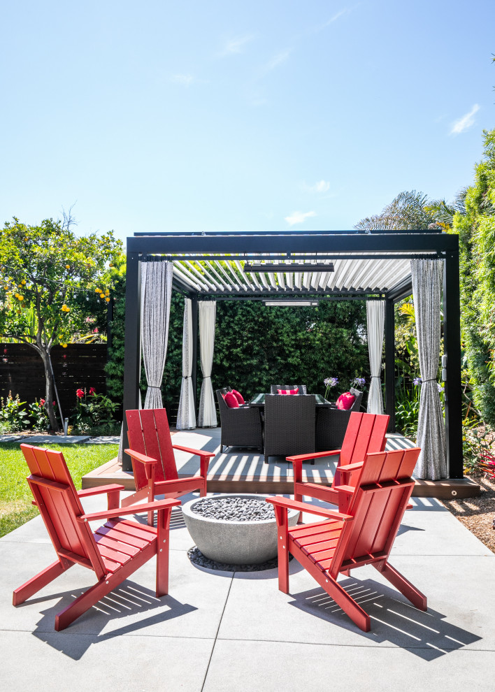 Immagine di un patio o portico minimalista dietro casa con un focolare, lastre di cemento e un gazebo o capanno