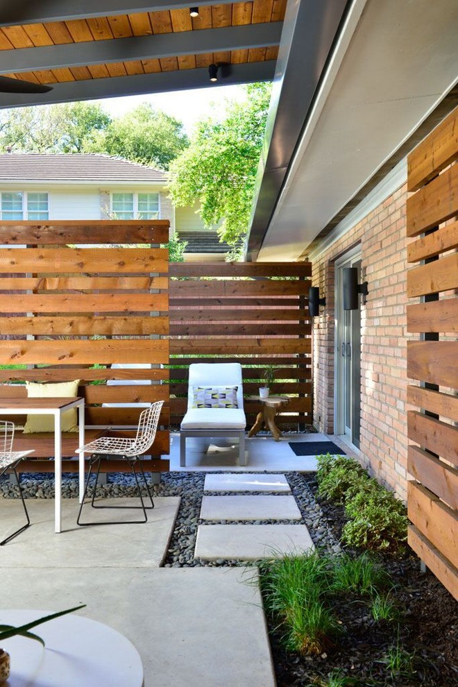 Immagine di un patio o portico minimalista dietro casa con lastre di cemento e un tetto a sbalzo