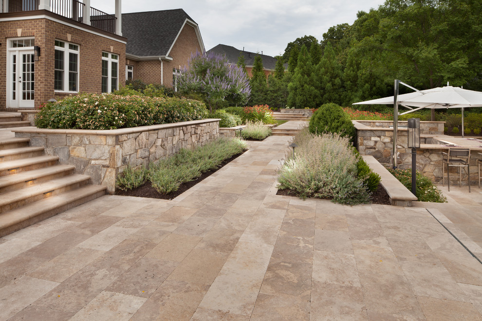 Immagine di un grande patio o portico chic dietro casa con pavimentazioni in pietra naturale