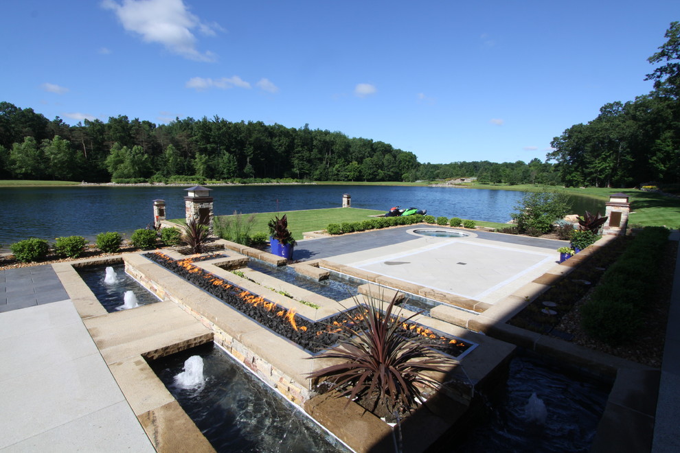 Patio fountain - huge contemporary backyard stone patio fountain idea in Grand Rapids with a roof extension