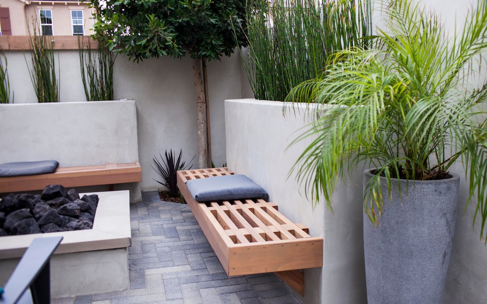 Example of a small minimalist backyard brick patio design in Orange County with no cover