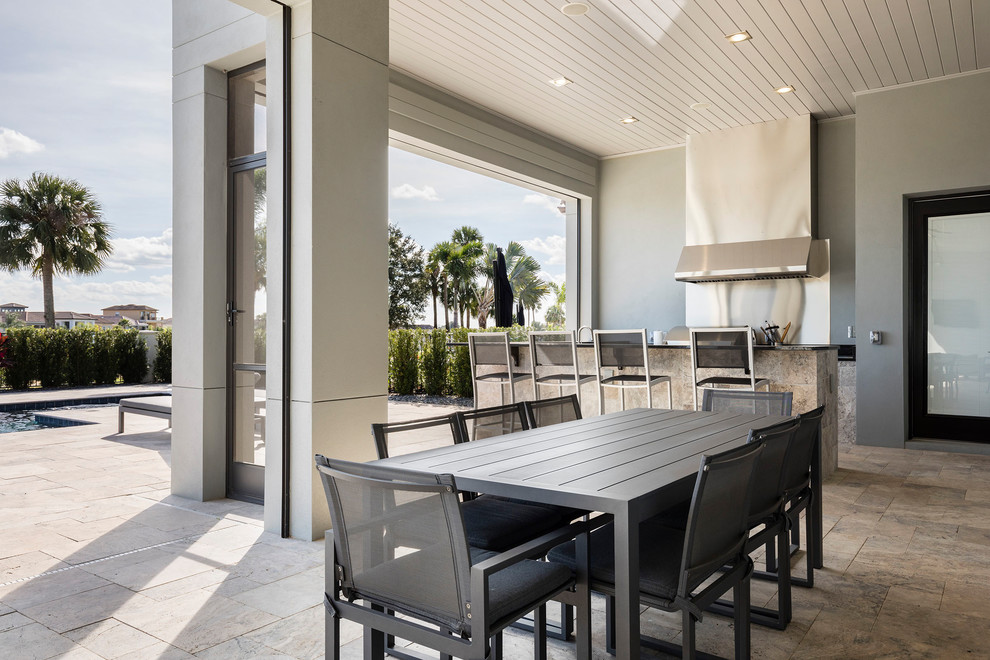 Photo of a large contemporary back patio in Orlando with an outdoor kitchen, tiled flooring and a roof extension.