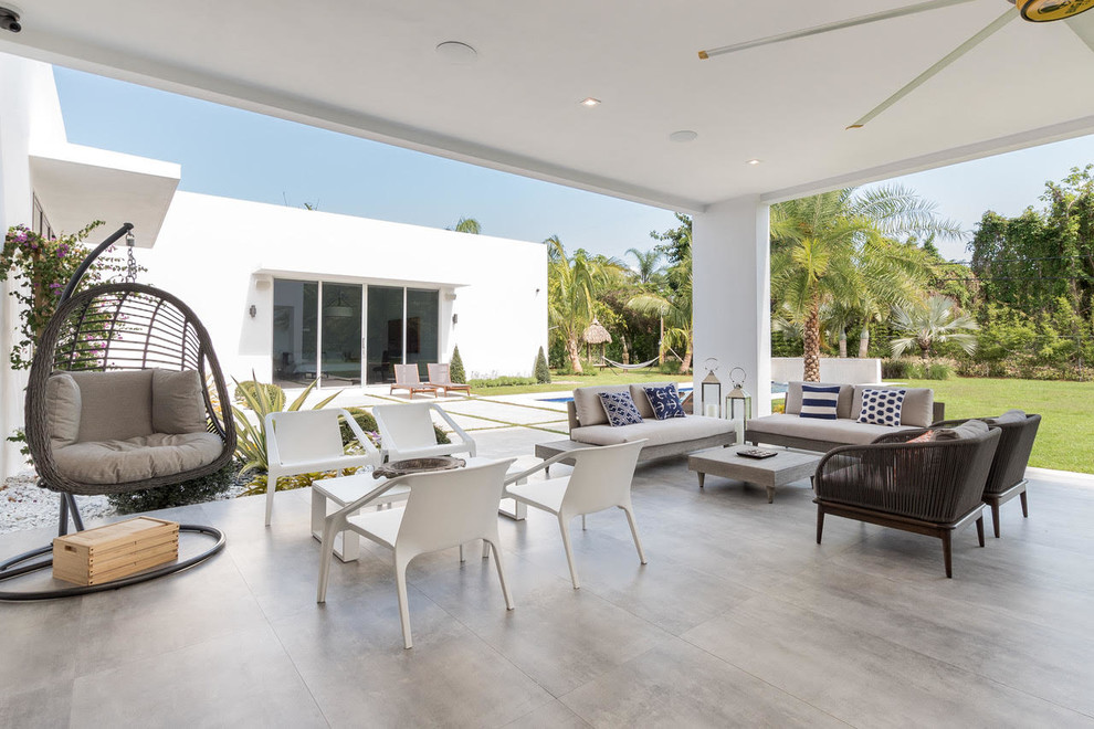Large minimalist backyard concrete paver patio kitchen photo in Miami with a roof extension