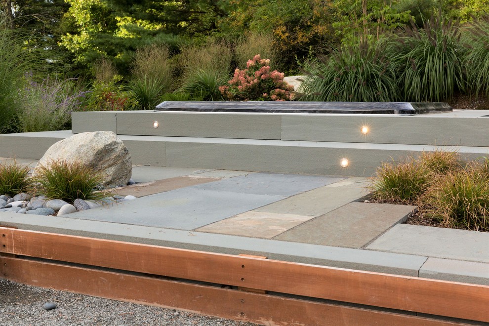 Modelo de patio moderno en patio trasero con adoquines de piedra natural