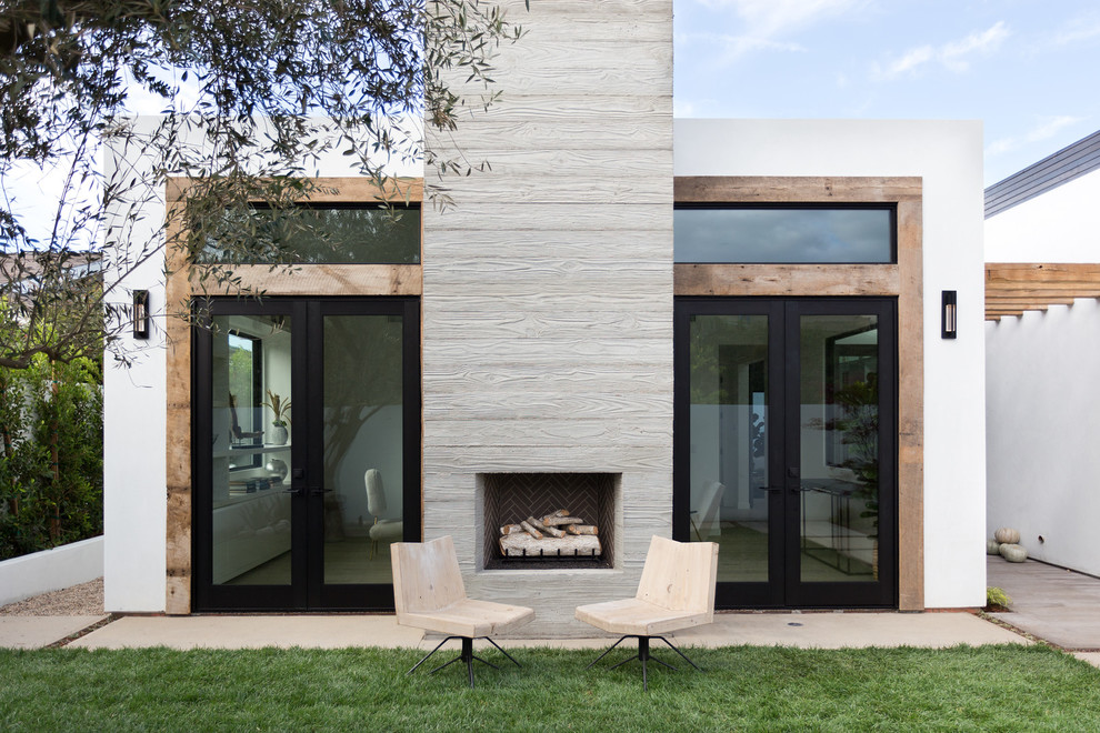 Ispirazione per un patio o portico moderno dietro casa con pavimentazioni in cemento, nessuna copertura e un caminetto