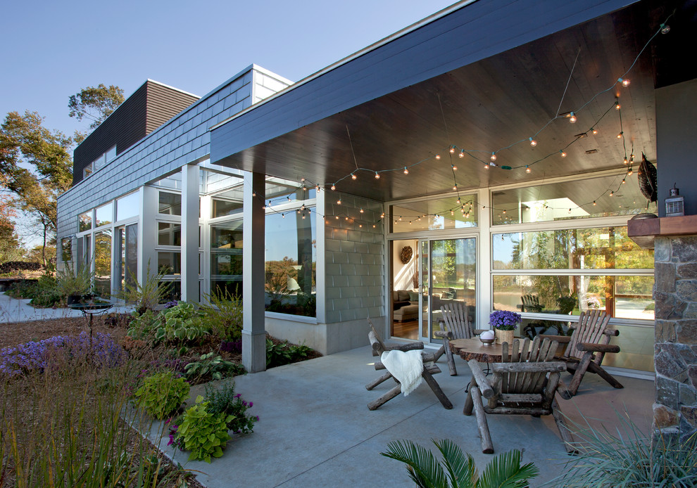 Idee per un patio o portico design di medie dimensioni e dietro casa con un focolare, lastre di cemento e un tetto a sbalzo