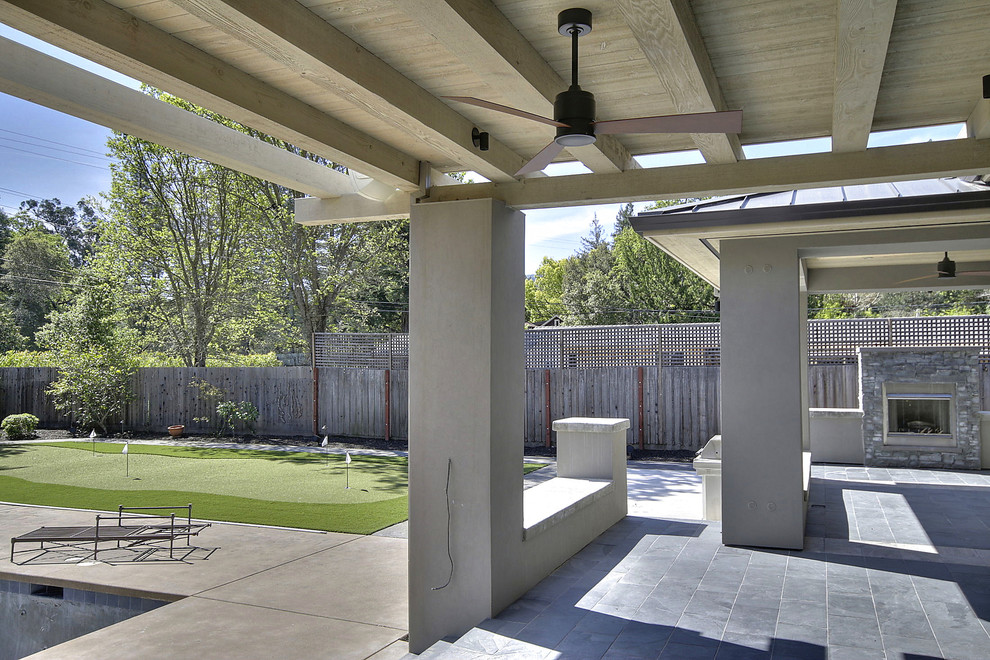 Inspiration pour une terrasse arrière design de taille moyenne avec un foyer extérieur, une dalle de béton et un gazebo ou pavillon.