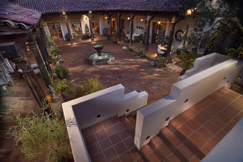 Immagine di un grande patio o portico mediterraneo in cortile con fontane, piastrelle e un tetto a sbalzo
