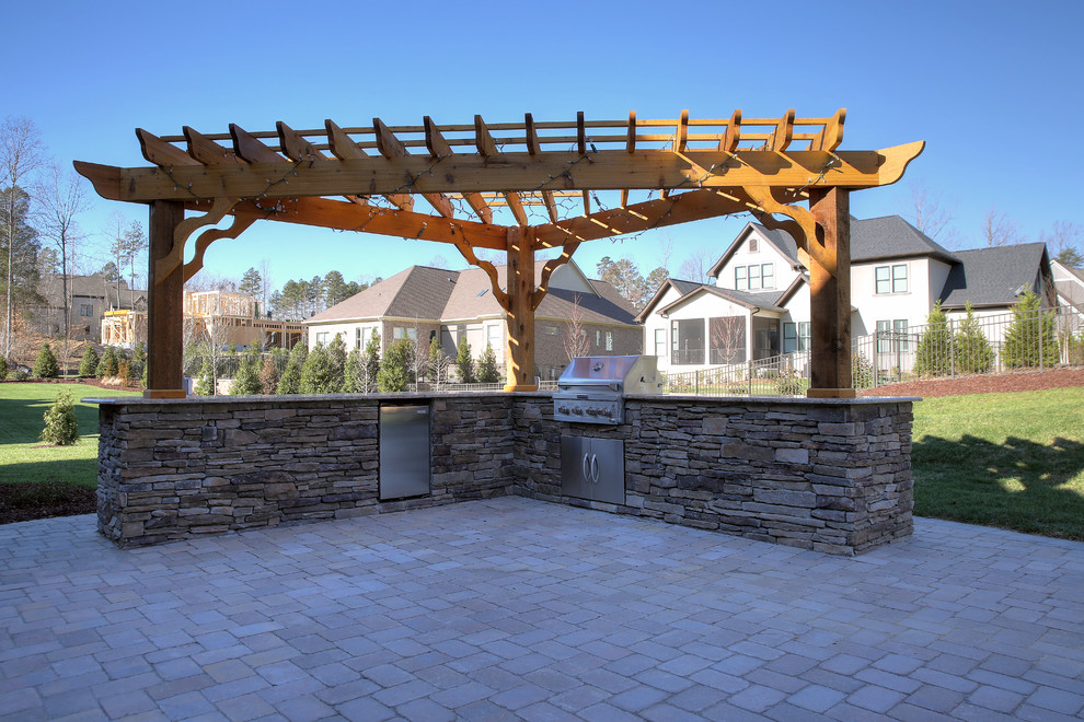 Idee per un grande patio o portico american style dietro casa con un focolare, pavimentazioni in pietra naturale e una pergola