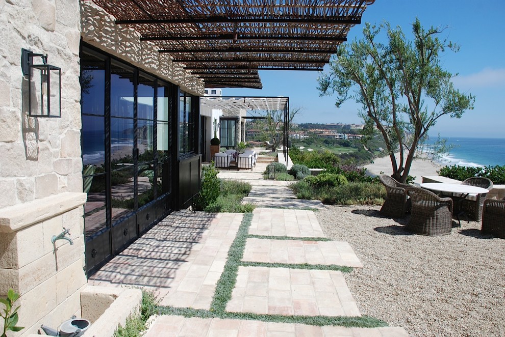Expansive nautical back patio in Orange County with gravel, a fire feature and a pergola.