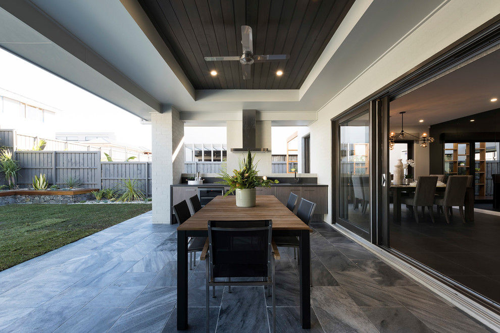 Idée de décoration pour une terrasse arrière design avec une cuisine d'été, du carrelage et une extension de toiture.