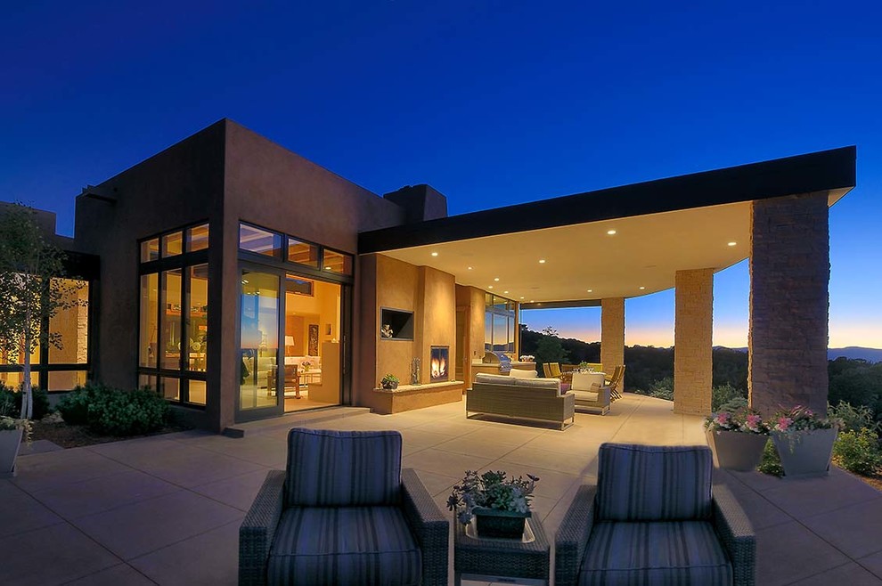 Inspiration pour une grande terrasse arrière design avec un foyer extérieur, du carrelage et une extension de toiture.