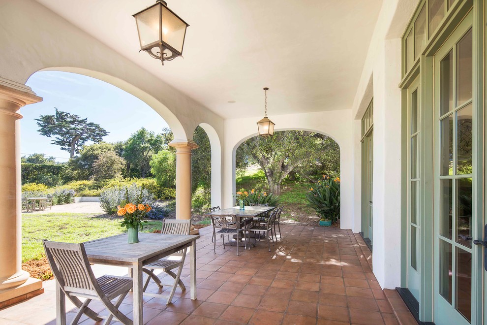 This is an example of a large mediterranean back patio in Santa Barbara with tiled flooring and a roof extension.