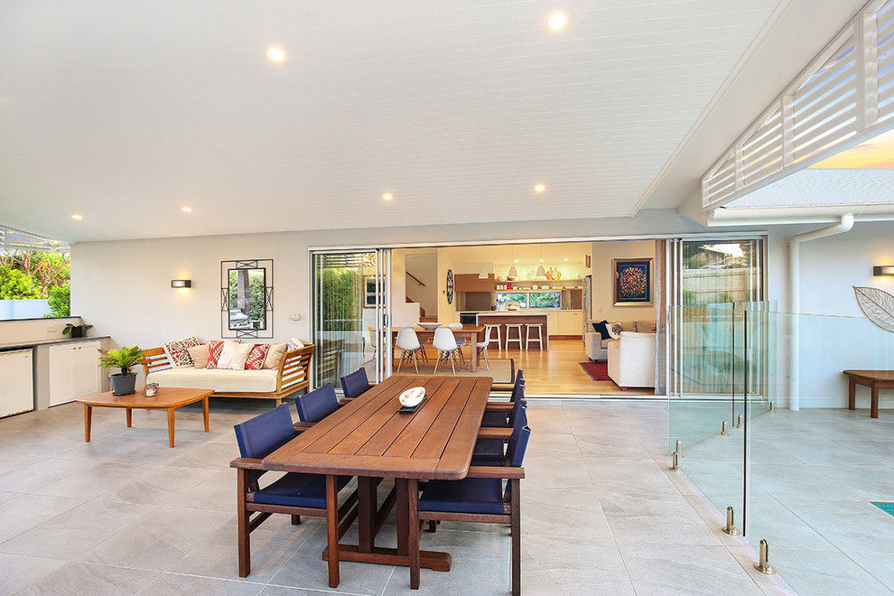 Photo of a large contemporary side patio in Sunshine Coast with tiled flooring and a roof extension.