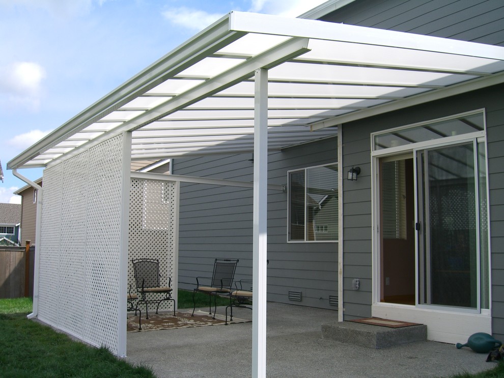 Ispirazione per un patio o portico chic dietro casa e di medie dimensioni con lastre di cemento e un parasole