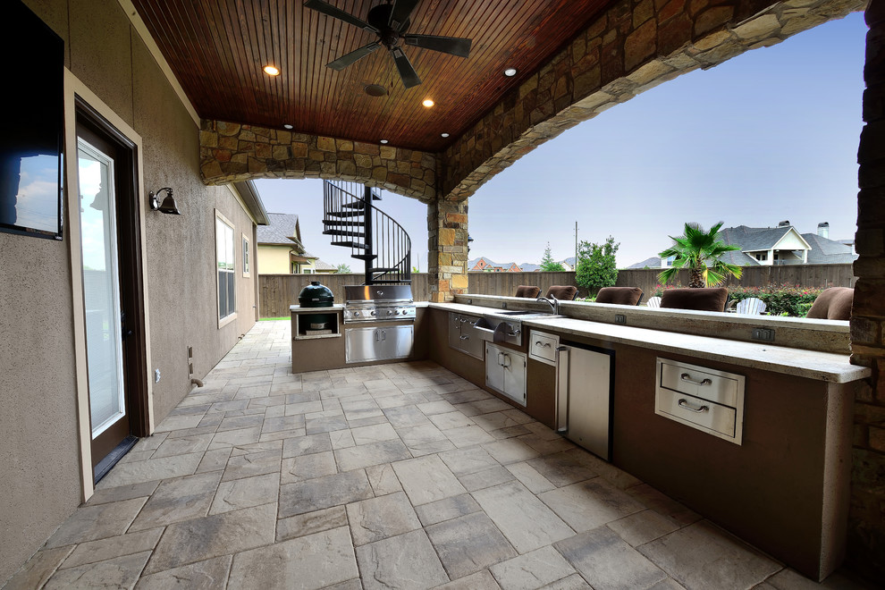 Large elegant backyard stamped concrete patio kitchen photo in Houston with a roof extension