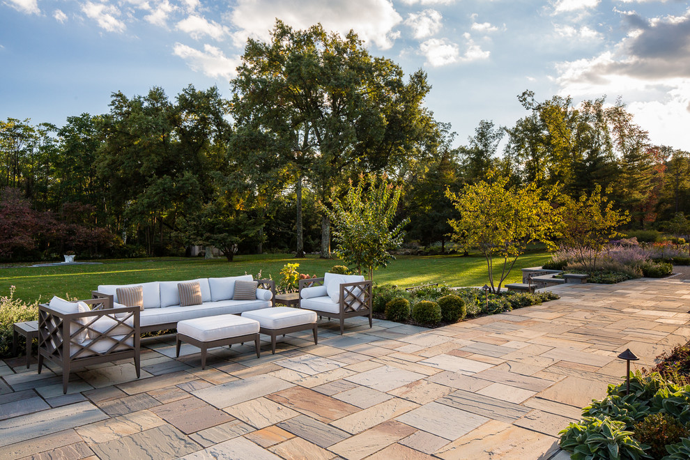 Ejemplo de patio clásico grande en patio trasero con adoquines de piedra natural