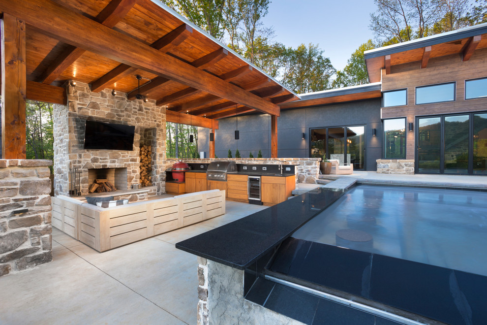 Huge trendy backyard concrete patio photo in Other with a fireplace and a pergola