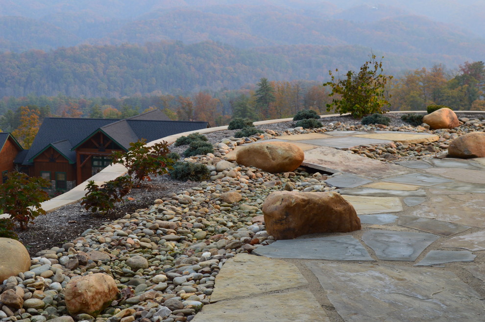 Modelo de patio rústico grande sin cubierta en patio trasero con brasero y adoquines de piedra natural