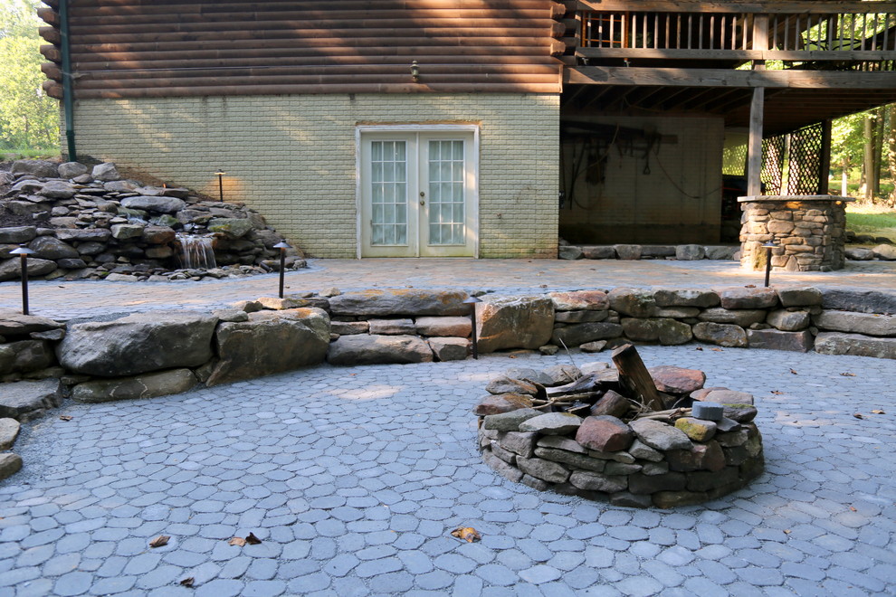 Cette image montre une terrasse arrière chalet de taille moyenne avec un foyer extérieur, des pavés en béton et aucune couverture.