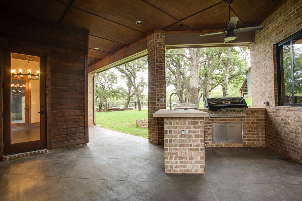 Inspiration pour une grande terrasse arrière chalet avec une cuisine d'été, une dalle de béton et une extension de toiture.