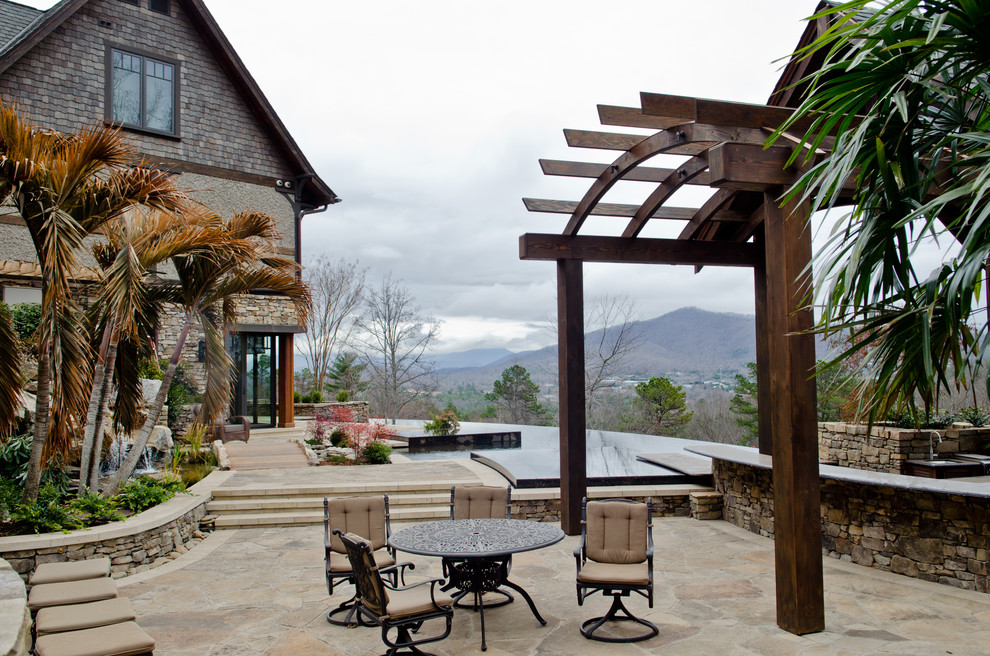 Elegant stone patio photo in Other with a pergola