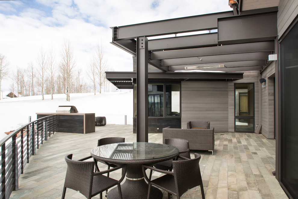 Réalisation d'une terrasse latérale design avec une cuisine d'été et une extension de toiture.