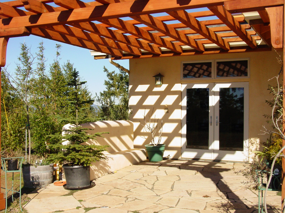 Aménagement d'une petite terrasse arrière classique avec des pavés en pierre naturelle et une pergola.