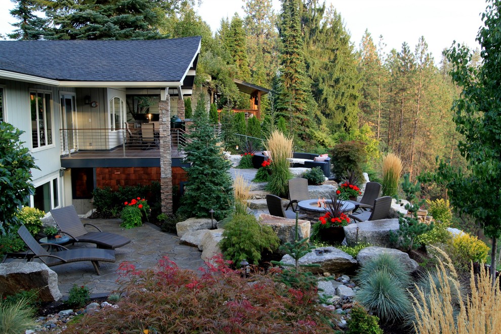 Ejemplo de patio contemporáneo en patio trasero y anexo de casas con brasero y adoquines de piedra natural