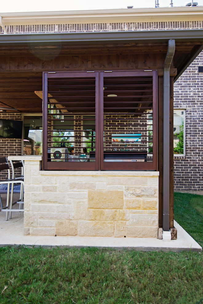 Réalisation d'une grande terrasse arrière tradition avec une cuisine d'été, du béton estampé et une extension de toiture.