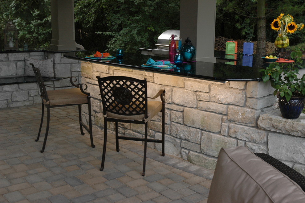 Immagine di un grande patio o portico tropicale dietro casa con un focolare, pavimentazioni in pietra naturale e un gazebo o capanno