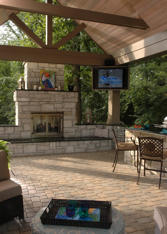 Photo of a large world-inspired back patio in Cincinnati with a fire feature, natural stone paving and a gazebo.