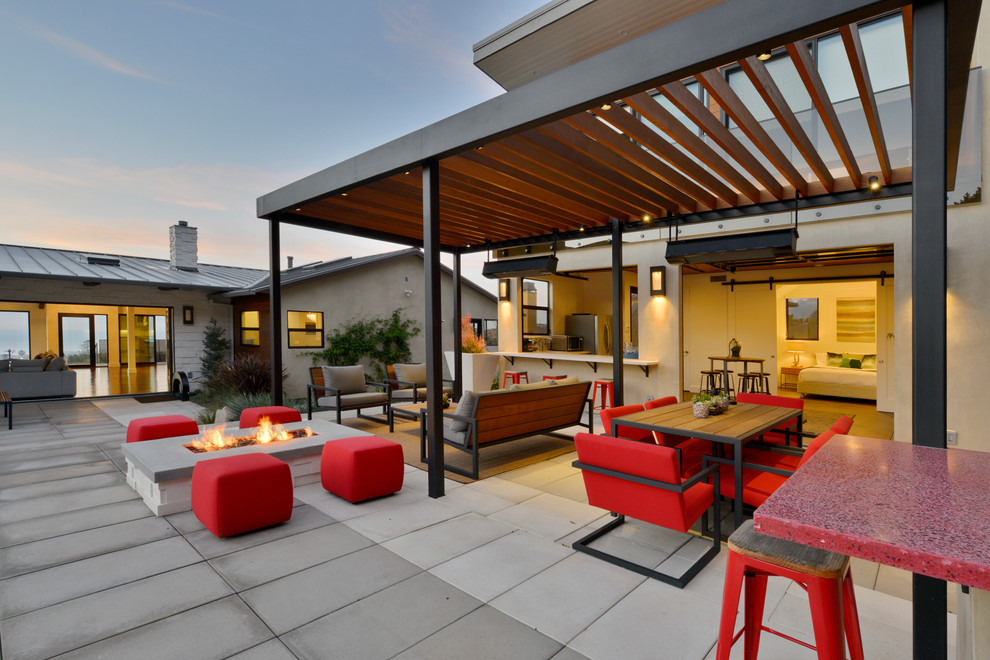 Réalisation d'une terrasse design avec un foyer extérieur et une pergola.