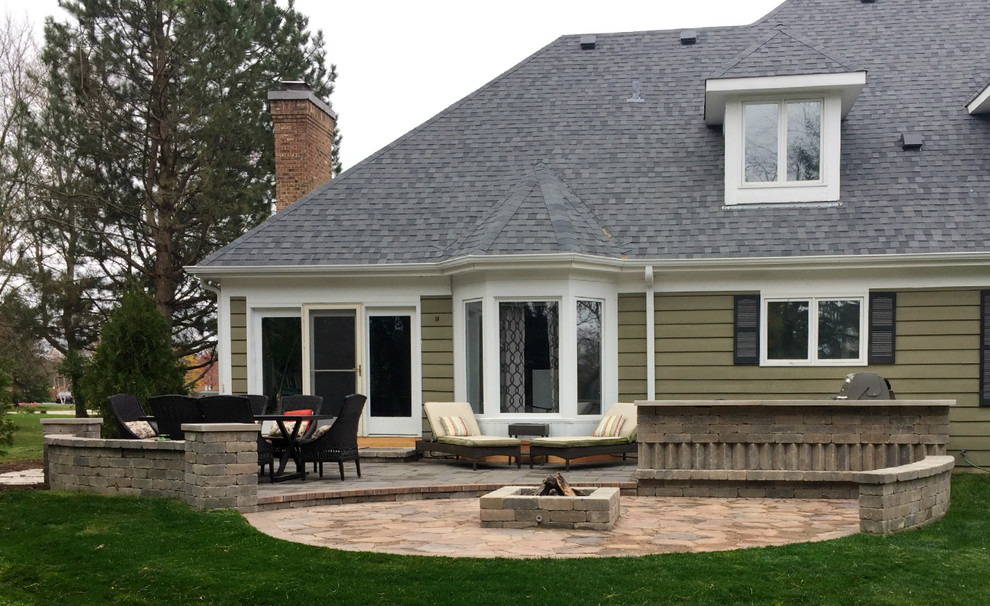 Diseño de patio clásico grande sin cubierta en patio trasero con brasero y adoquines de ladrillo