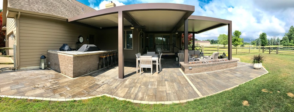 Example of a large classic backyard stamped concrete patio design in Detroit with a fire pit and a pergola